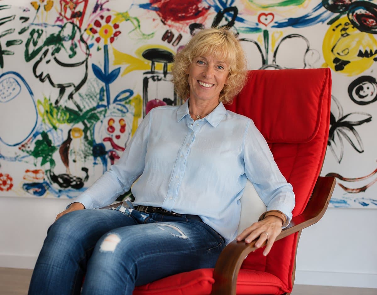 Marion Christ in ihrer Praxis vor einem farbenfrohen Kinderbild